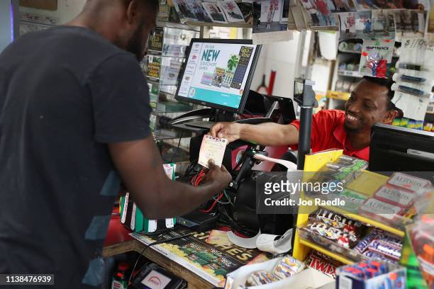 Jackson Mauvais sells a Powerball ticket to George Hollins at the Shell Gateway store on March 26, 2019 in Boynton Beach, Florida. Wednesday's...