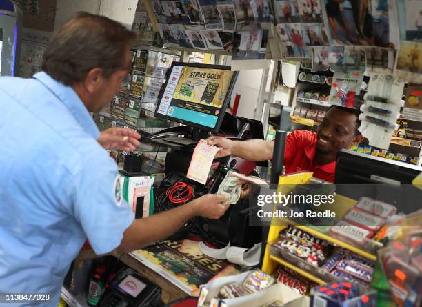 Jackson Mauvais sells a Powerball ticket to Ken Meese at the Shell Gateway store on March 26, 2019 in Boynton Beach, Florida. Wednesday's Powerball...