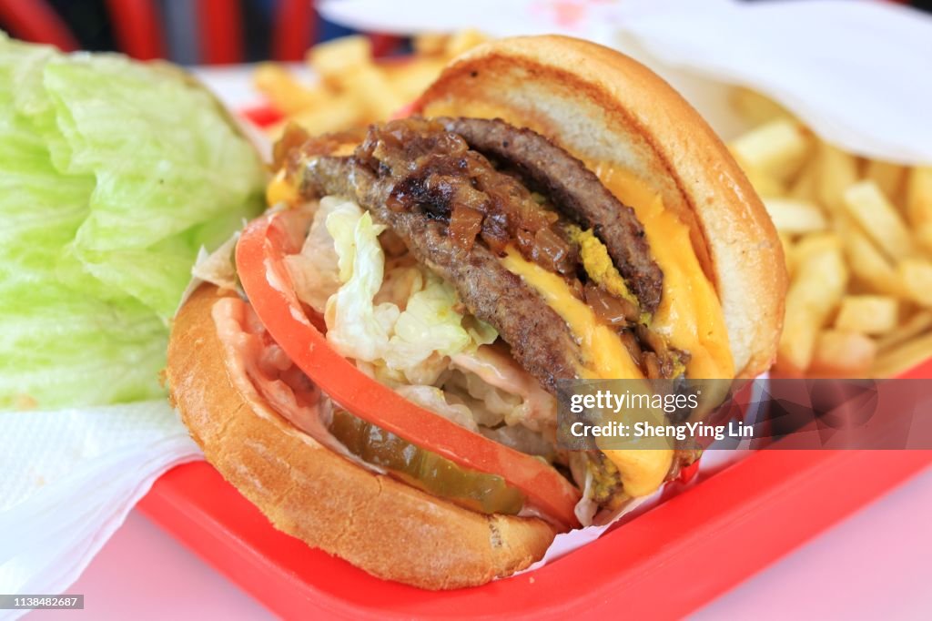 In n Out Double Double cheeseburger with animal style, with french fries and burger with protein style as background