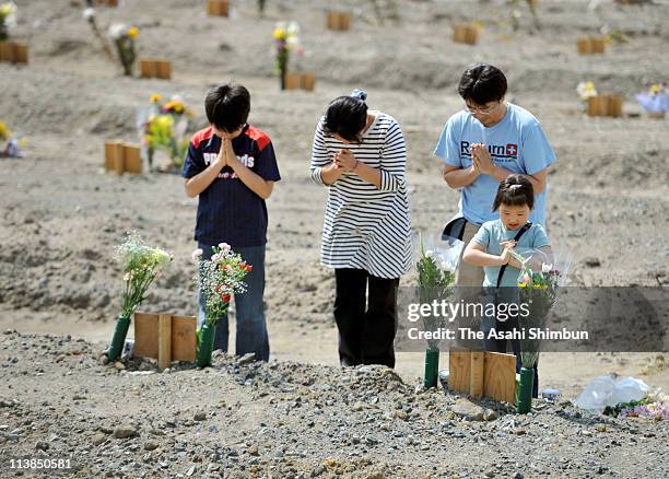 Family members of a tsunami victim offer the bunch of flowers to the temporary burial site on mother's day, May 8, 2011 in Ishinomaki, Miyagi, Japan....