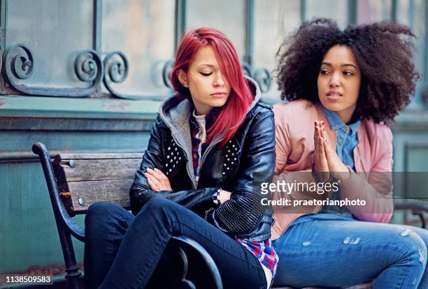 girl is trying to calm down her sulking girlfriend - forgiveness stock pictures, royalty-free photos & images