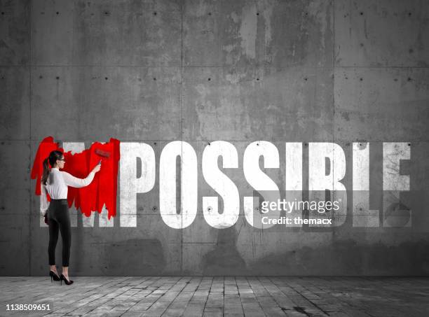 young businesswoman impossible text on the wall using red paint roller - make a change stock pictures, royalty-free photos & images