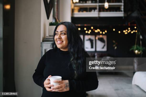 portret van een jonge vrouw met koffie in haar centrum van los angeles appartement - indian lifestyle stockfoto's en -beelden