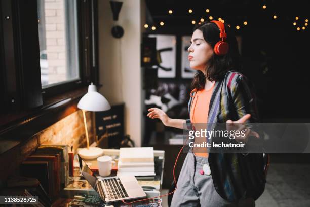 young millennial dancing to the music in her downtown los angeles apartment - rock n roll vintage stock pictures, royalty-free photos & images