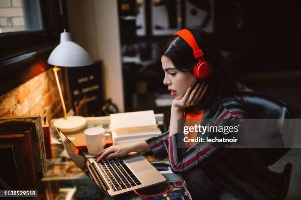 young millennial using laptop while listening to music in her downtown los angeles apartment - hipster office stock pictures, royalty-free photos & images