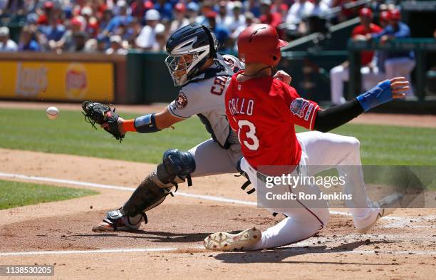 Joey Gallo of the Texas Rangers slides safely into home plate to score as Robinson Chirinos of the Houston Astros takes the throw during the first...