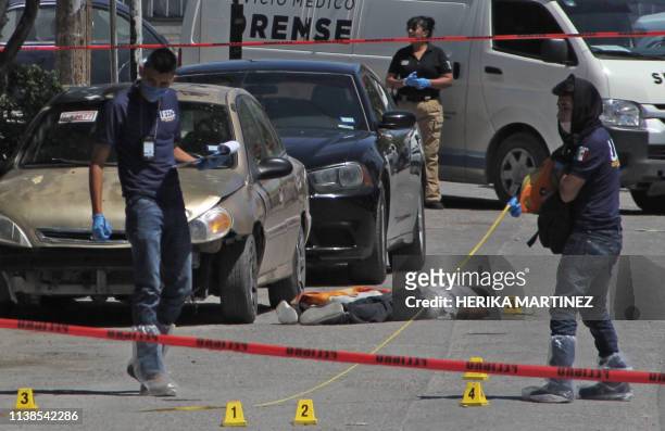 Forensic experts and investigators of the prosecution office work at the crime scene next to a man's corpse in Ciudad Juarez, Mexico, on April 20,...