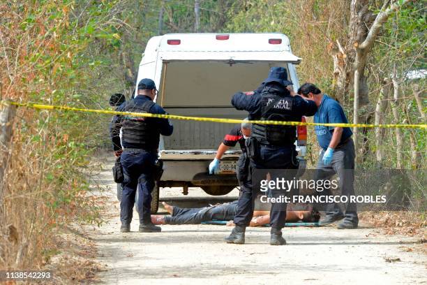 Forensic experts,investigators of the prosecution office and policemen work at the crime scene next to a man's corpse in the outskirts of Acapulco,...