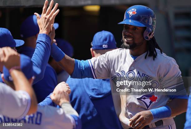 Alen Hanson of the Toronto Blue Jays is congratulated by teammates after he scored against the Oakland Athletics in the top of the third inning of a...