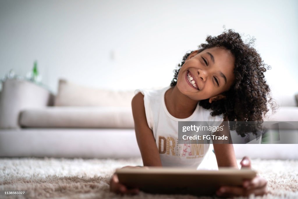 Menina Latin que usa a tabuleta digital em casa-retrato