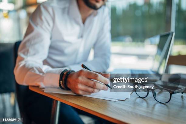 businessman signing contract in cafe - man signing paper stock pictures, royalty-free photos & images