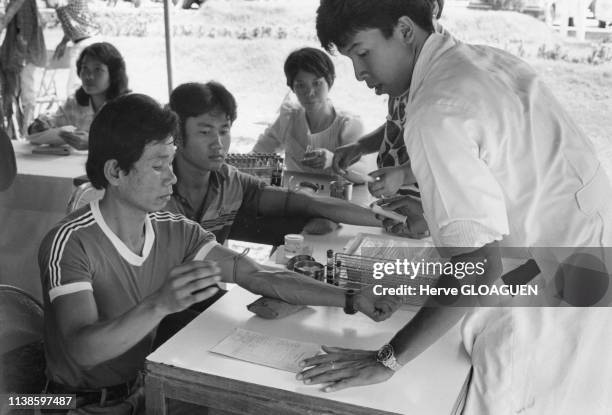 Prise de sang pour le dépistage du sida pour les ouvriers désirant partir travailler dans les pays du golfe Persique, en 1986, à Bangkok, Thaïlande.