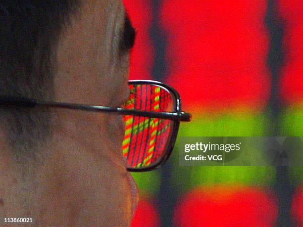 An investor watches the electronic board at a stock exchange hall on May 9, 2011 in Haikou, Hainan Province of China. The power companies and train...