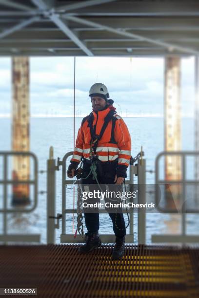 Rope access technicia preparing for work on offshore platform in wet-suit