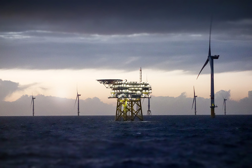Offshore platform - substation and wind farm in sunset