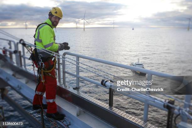 Rope access technician making inspection and repairs of railing with transfer vessel guarding