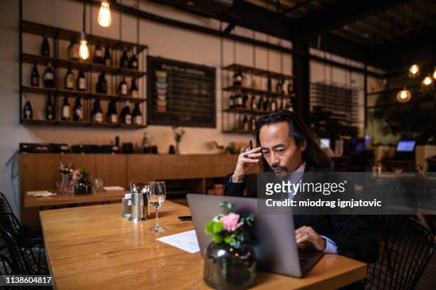 chinese businessman using laptop in cafe - offbeat documentation stock pictures, royalty-free photos & images