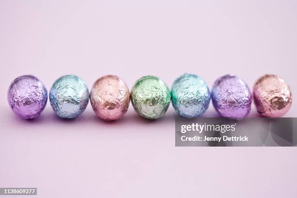 small easter eggs in a row - chocolate foil stock-fotos und bilder