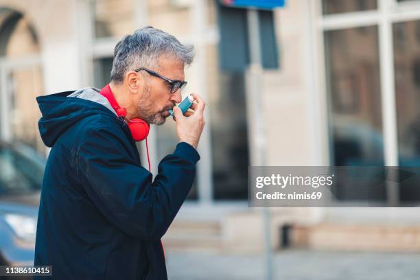 man using an asthma inhaler - reliever asthma inhaler stock pictures, royalty-free photos & images
