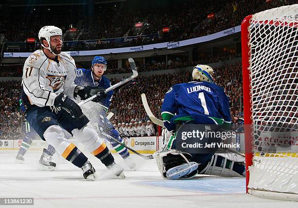 Christian Ehrhoff of the Vancouver Canucks looks on as David Legwand of the Nashville Predators scores a shorthanded goal on Roberto Luongo of the...