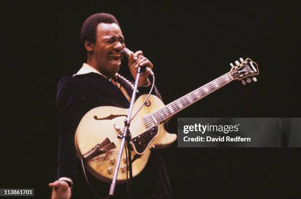 George Benson, U.S. Singer-songwriter and musician, singing into a microphone during a live concert performance, circa 1980. Benson also has a guitar...