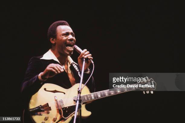 George Benson, U.S. Singer-songwriter and musician, singing into a microphone during a live concert performance, circa 1980. Benson also has a guitar...
