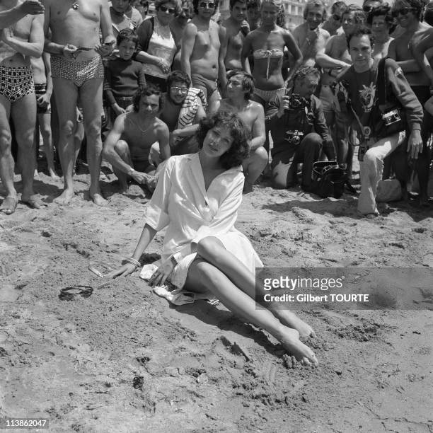Sylvia Kristel poses on a beach with fans and photographers behind her in Cannes during the Cannes Film Festival in 1970's in Cannes, France.