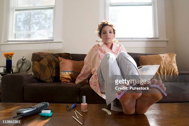 young woman giving herself a pedicure - toe separators stock pictures, royalty-free photos & images