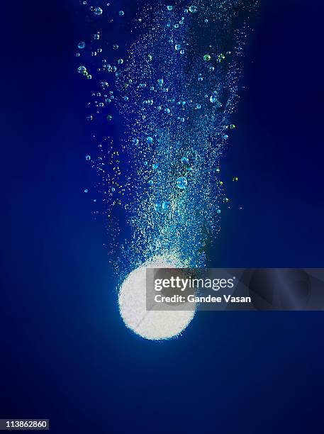 effervescent tablet dissolving in water - red blue background stockfoto's en -beelden