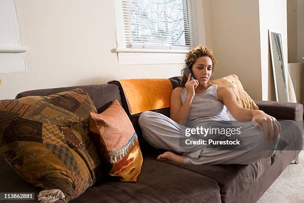 young woman relaxing on sofa talking on phone - jogging pants 個照片及圖片檔