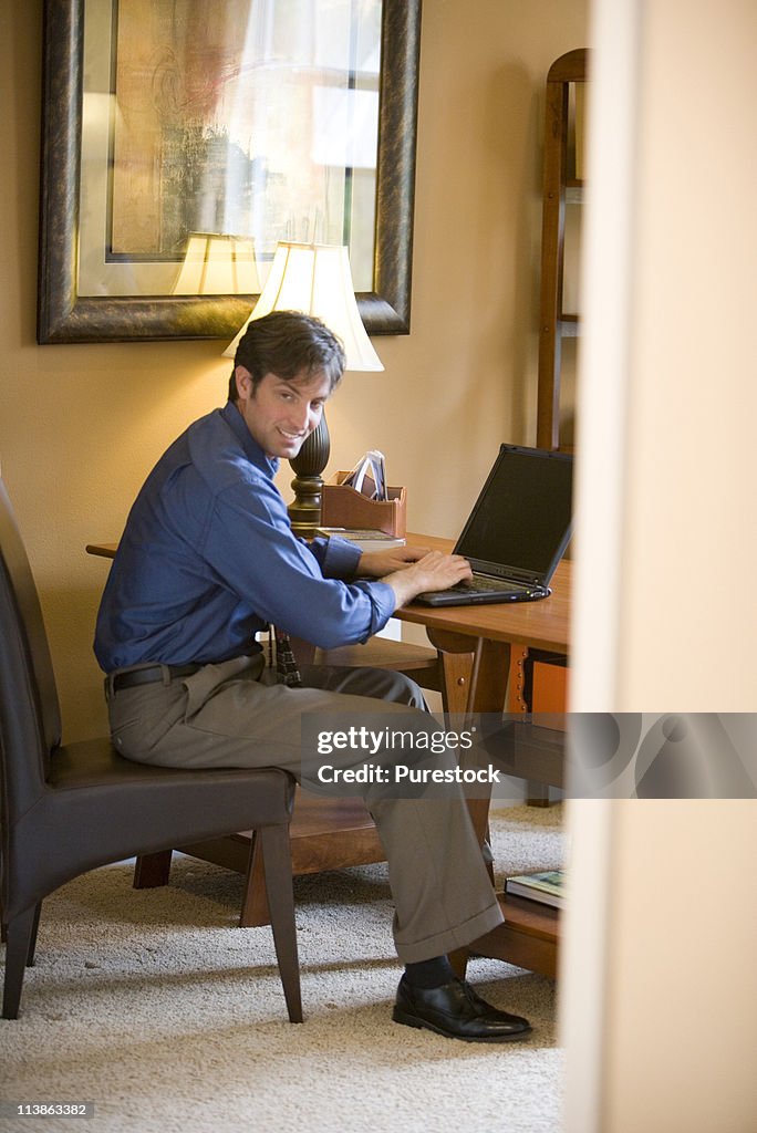 Man using laptop computer in the study of his home