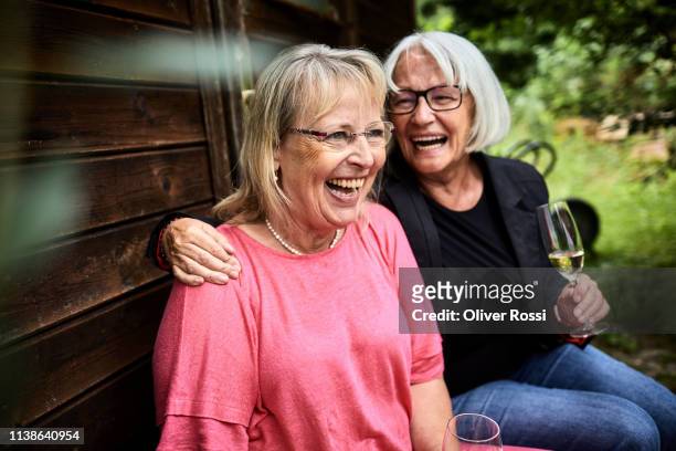 laughing senior women with drinks sitting at garden shed - senior women wine stock pictures, royalty-free photos & images