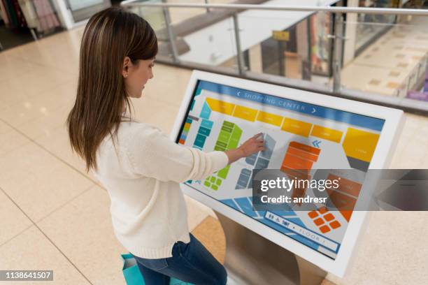 female shopper looking for a store on a map at the shopping center - navigational equipment stock pictures, royalty-free photos & images