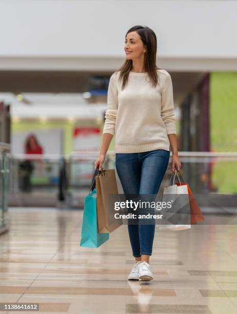 happy woman walking at the shopping center - latin american and hispanic shopping bags stock pictures, royalty-free photos & images