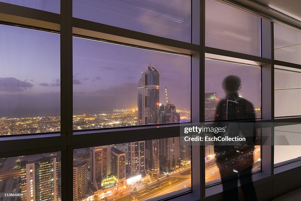 Man looking at illuminated Dubai skyline at dusk