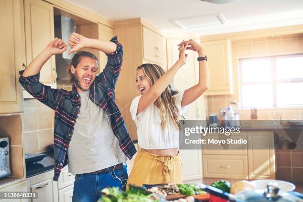 we just can't ignore a good song! - young couple cooking stock pictures, royalty-free photos & images