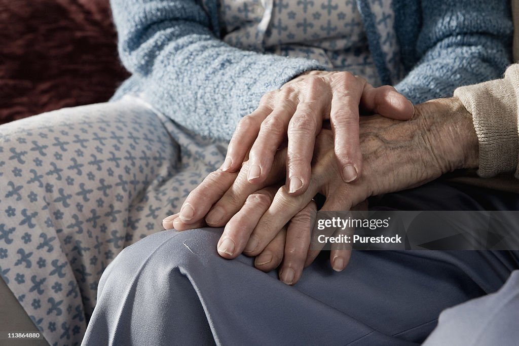 Close up of holding hands of senior couple
