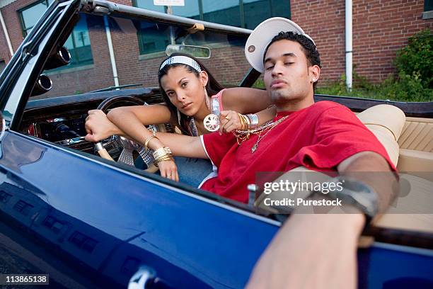 portrait of a young hip-hop couple sitting in a pimped-up vintage car - pimped car foto e immagini stock