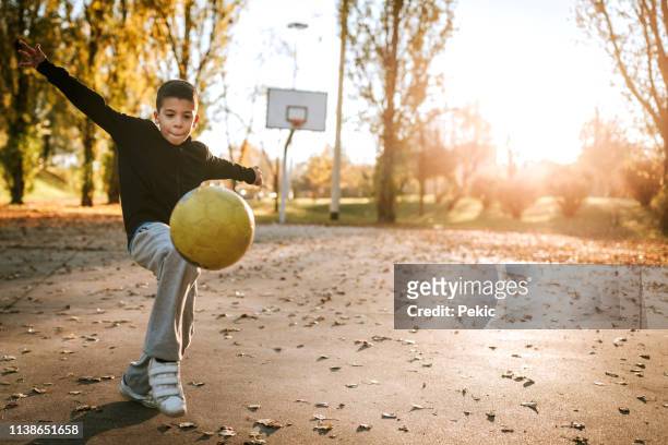 junge spielen mit fußball im freien - street football stock-fotos und bilder