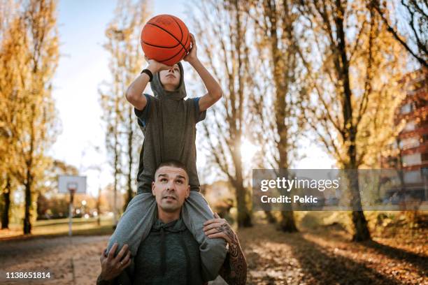 father helping son to make a score in basketball - carrying on shoulders stock pictures, royalty-free photos & images