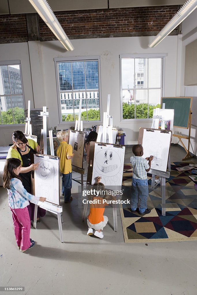 An art teacher with her student drawing on easels in art class