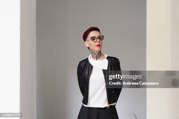 a woman with short red hair and tattoos is posing for a portrait. - ミッドアダルト ストックフォトと画像