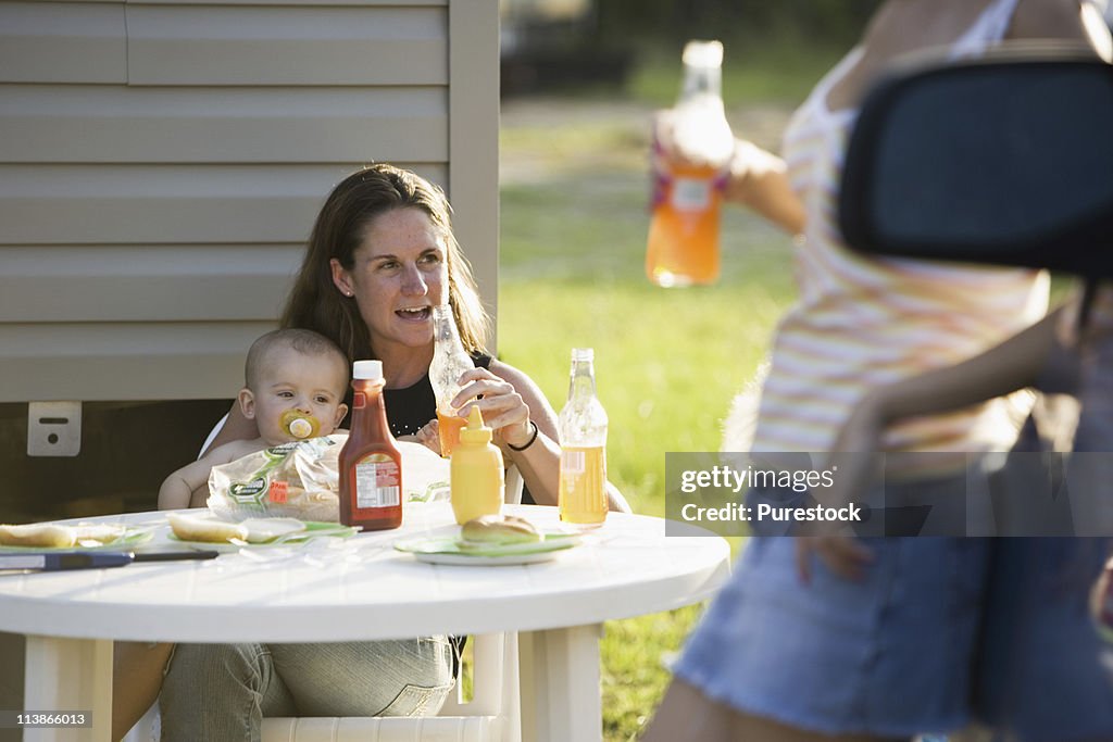 Woman holding baby sitting at picnic table