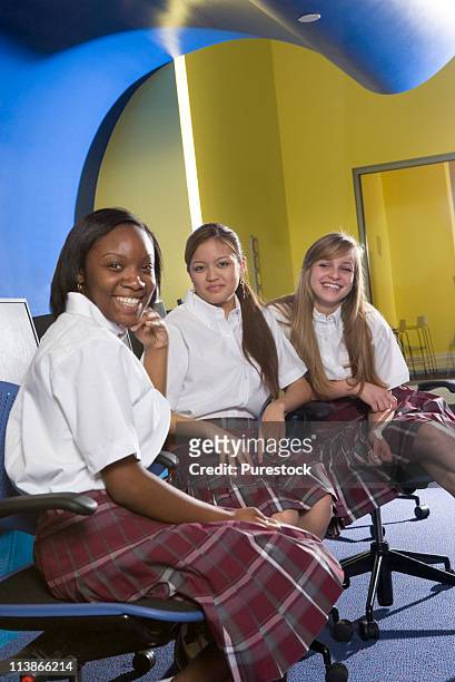 portrait of three students wearing uniforms in a computer classroom - 12 year old in skirt stock pictures, royalty-free photos & images