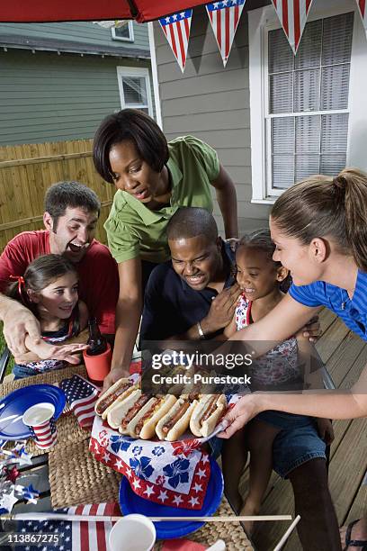 two families on backyard patio enjoying a cookout on the 4th of july - amerikanische südstaaten flagge stock-fotos und bilder