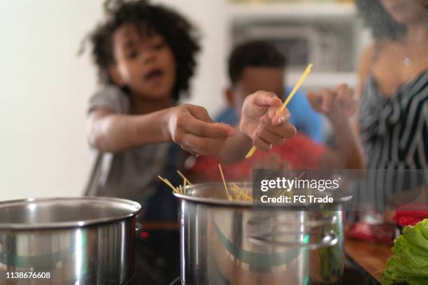 family cooking together at kitchen - cooking pasta stock pictures, royalty-free photos & images