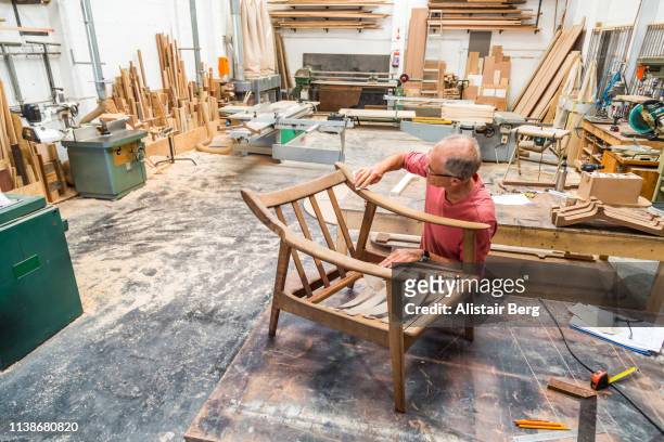 senior man restoring an old chair in a woodworking studio - designer einrichtung stock-fotos und bilder