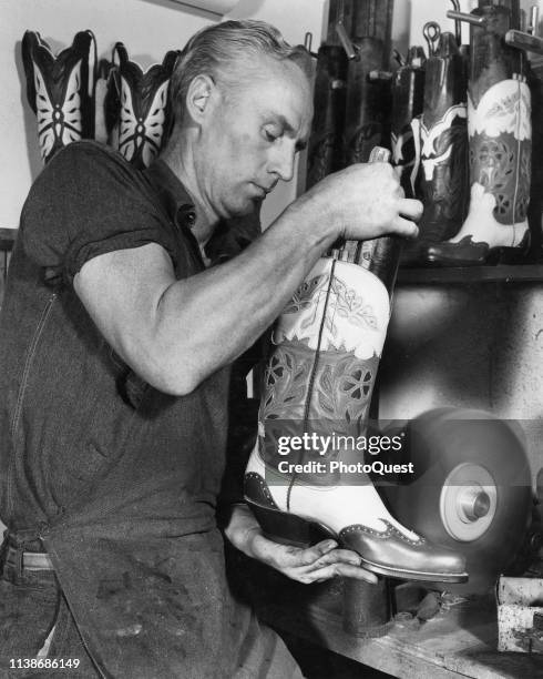 An unidentified Western Boot Company worker buffs a pair of finished boots as the last step before they are boxed and shipped, Tucson, Arizona, 1951.