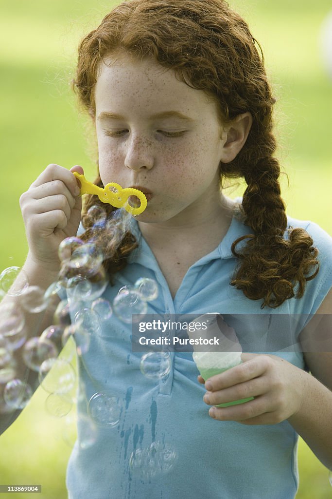 Girl blowing bubbles at a park