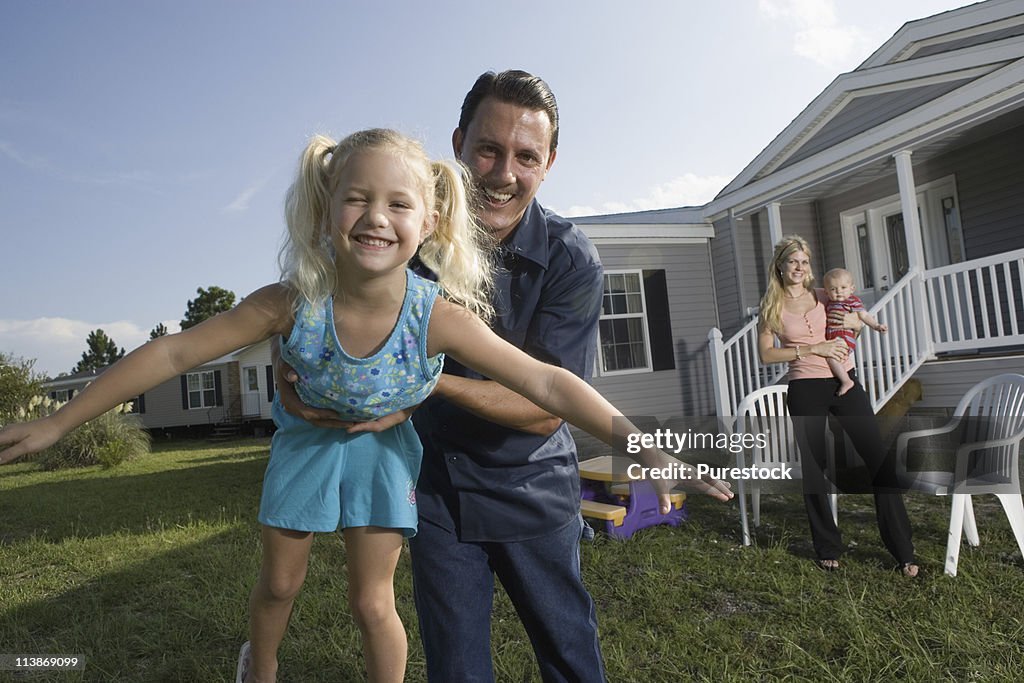 Portrait of a man playing with his family in front of a trailer home